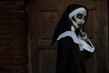 Kırmızı tuğla duvarın yanında korkunç bir rahibenin portresi. Cadılar Bayramı partisi görünüşü