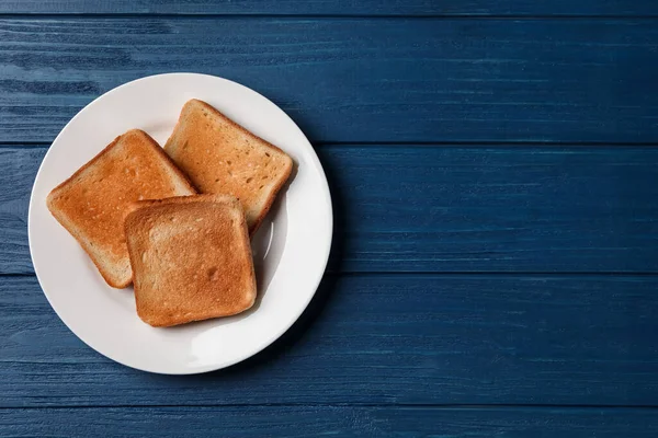 青い木製のテーブルの上においしいトーストパンのスライスとプレート トップビュー テキストのスペース — ストック写真