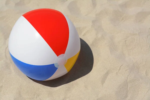 Colorful beach ball on sand, space for text