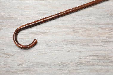 Elegant walking cane on light wooden table, top view. Space for text