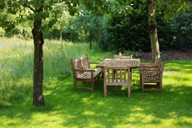 Empty wooden table with bench and chairs in garden