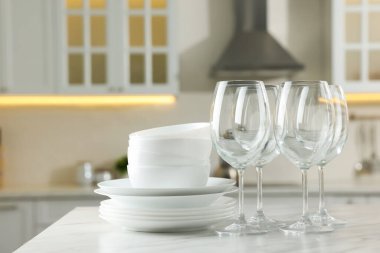 Mutfaktaki beyaz mermer masada farklı temiz bulaşık takımları ve bardaklar.
