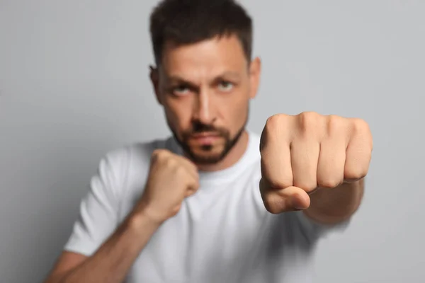 Man Gooit Punch Tegen Grijze Achtergrond Focus Vuist Ruimte Voor — Stockfoto