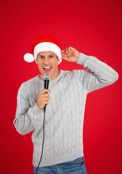 Щасливий Чоловік Капелюсі Санта Клауса Співає Мікрофоном Червоному Фоні Різдвяна — стокове фото