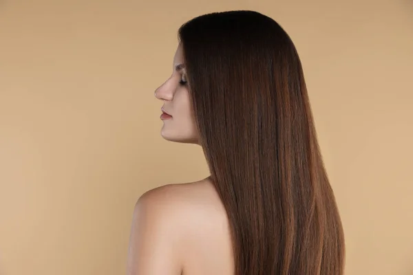 Young woman with strong healthy hair on beige background