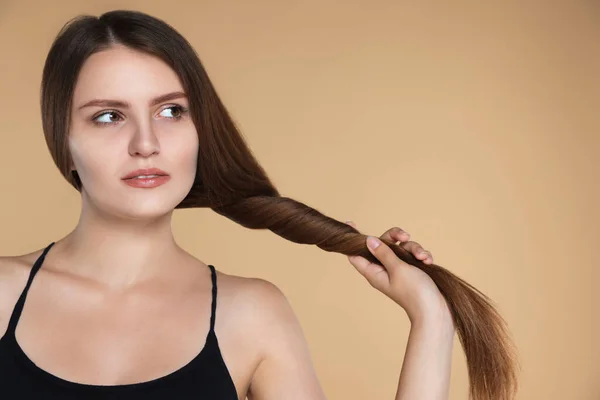 Young woman with strong healthy hair on beige background, space for text