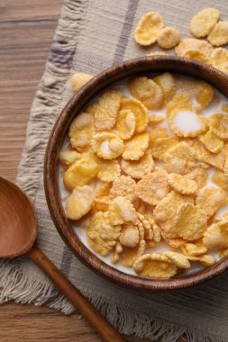 Tasty cornflakes with milk in bowl served on wooden table, flat lay