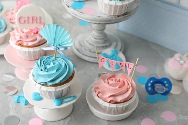 Gri masada bebek partisi için açık mavi ve pembe kremalı enfes kekler.