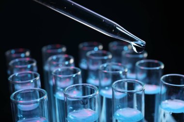 Siyah arkaplanda test tüpüne reaktör damlatılıyor, yakın plan. Laboratuvar analizi