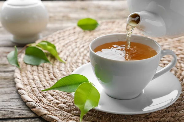 将绿茶倒入茶杯 茶碟放在桌上 — 图库照片