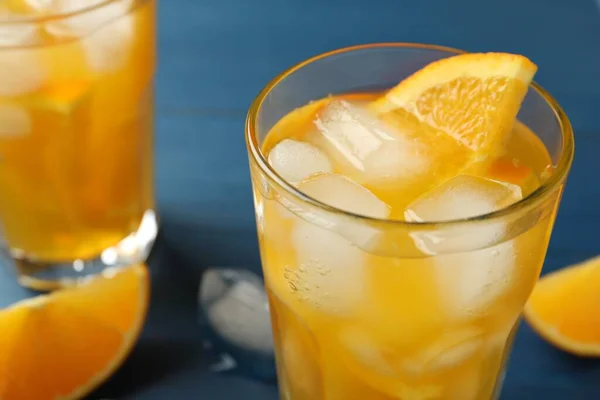 Delicious orange soda water on blue background, closeup