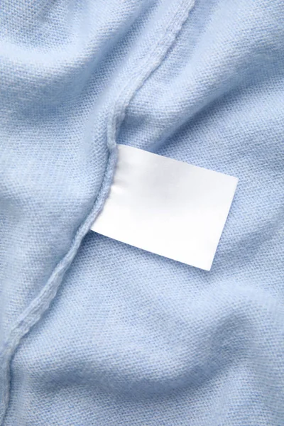 Warm light blue cashmere sweater with clothing label, closeup