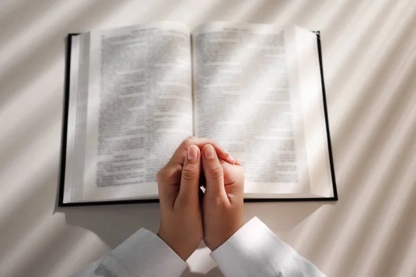 白いテーブルで聖書を祈りながら手を握っている女性の見解の上に — ストック写真