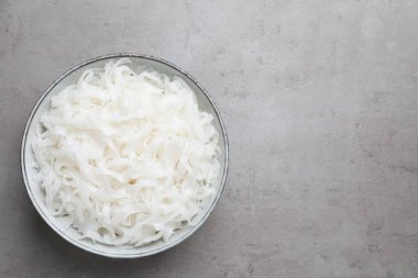 Açık gri masada pişmiş pirinç erişteli kase, üst manzara. Metin için boşluk