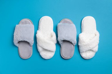 Açık mavi arka planda farklı yumuşak pofuduk terlikler.