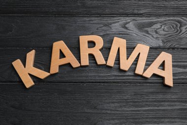 Karma kelimesi siyah arka planda ahşap harflerle yazıldı.