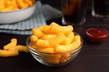 Crunchy cheesy corn snack on wooden table, closeup