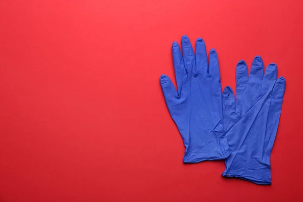 Pair of medical gloves on red background, flat lay. Space for text