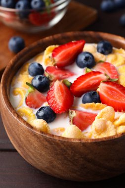Bir kase lezzetli gevrek mısır gevreği. Süt ve böğürtlen ahşap masada, yakın plan.