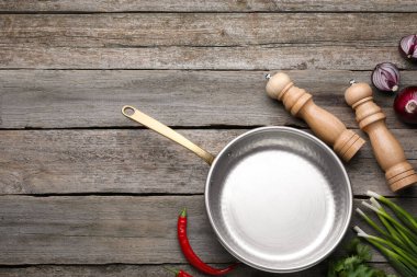 Flat lay composition with frying pan and fresh products on wooden table, space for text