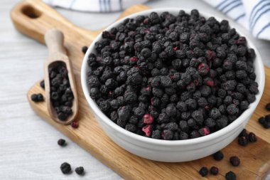 Bowl and scoop with dried blueberries on white wooden table