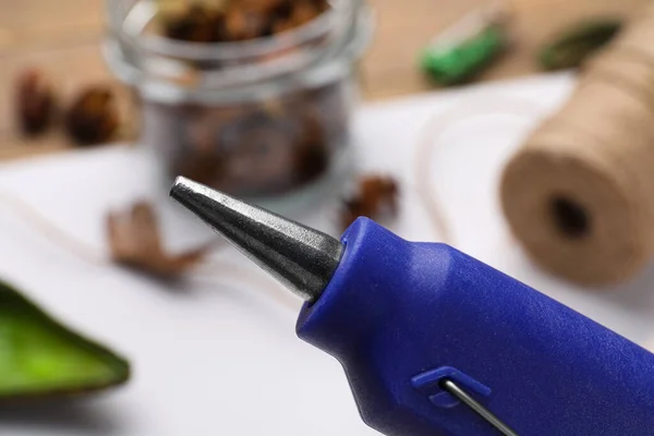 Hot glue gun over table with handicraft materials, closeup