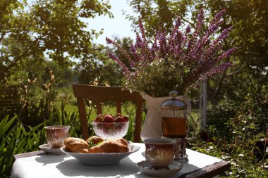 Beautiful bouquet of wildflowers on table served for tea drinking in garden
