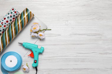 Sıcak tutkal tabancası ve el işi malzemeler beyaz ahşap masada, düz yerde. Metin için boşluk