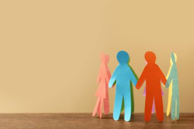 Birçok kağıt insan figürü bej arka plana karşı ahşap masada daire şeklinde duruyor, yazı için yer var. Çeşitlilik ve kapsama kavramı