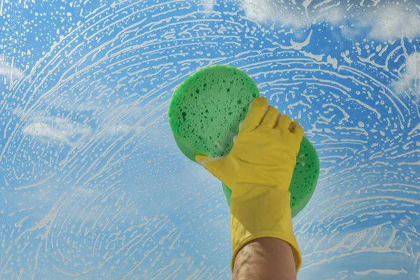 Woman cleaning glass with sponge indoors, closeup