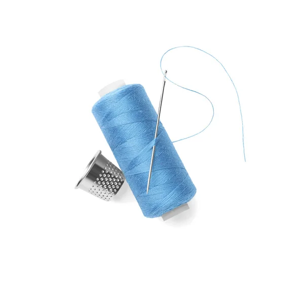 白い背景に針とツヤ感のある薄青色の縫製糸のスプール トップビュー — ストック写真