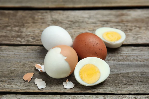 Hard boiled eggs and pieces of shell on wooden table