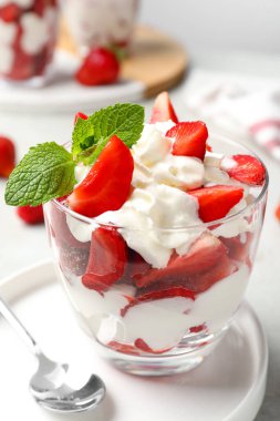 Açık gri masada servis edilen kremşantili lezzetli çilekler.