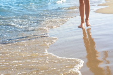 Denize yakın kumsalda yürüyen bir kadın, yakın çekim. Metin için boşluk