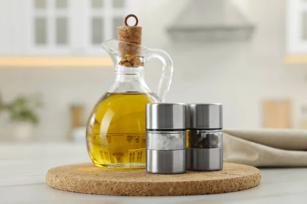 Salt and pepper mills with bottle of oil on table in kitchen