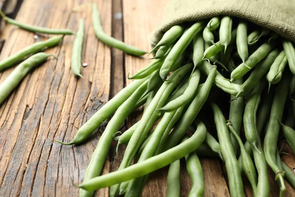 Fresh green beans in bag on wooden table, closeup