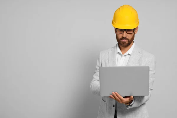 Professional engineer in hard hat with laptop on white background, space for text