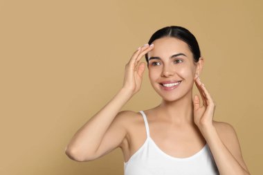 Beautiful young woman with perfect skin on beige background, space for text