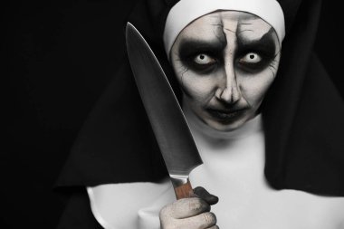 Siyah arka planda bıçağı olan korkunç şeytani bir rahibe. Cadılar Bayramı partisi görünüşü