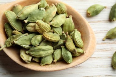 Beyaz ahşap masada kakule kapsüllü kaşık, yakın plan.