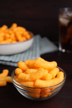Crunchy cheesy corn snack on wooden table, closeup