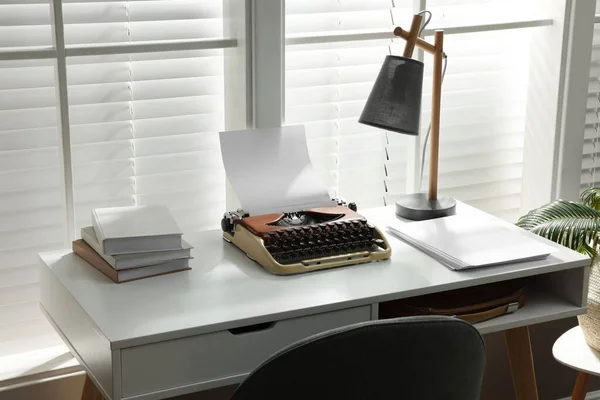 Comfortable writer\'s workplace with typewriter on desk in front of window