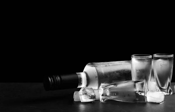 ウォッカのボトルと黒を背景にテーブルの上に氷とショットグラス テキストのスペース — ストック写真