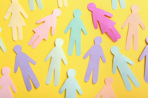 Many different paper human figures on yellow background, flat lay. Diversity and inclusion concept
