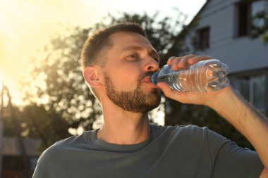 Man drinking water outdoors on hot summer day. Refreshing drink