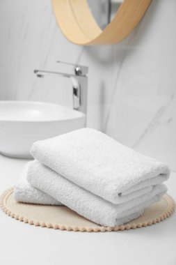 Banyodaki beyaz masada katlanmış banyo havluları.