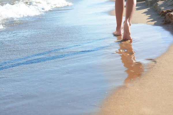 Woman walking on sandy beach near sea, closeup. Space for text