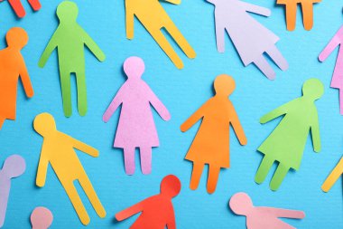 Many different paper human figures on light blue background, flat lay. Diversity and inclusion concept