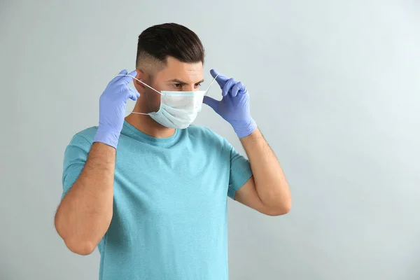 Άντρας Ιατρικά Γάντια Που Φοράει Προστατευτική Μάσκα Προσώπου Γκρι Φόντο — Φωτογραφία Αρχείου