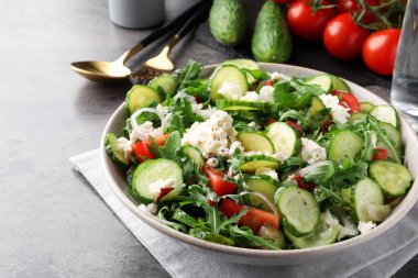 Gri masada servis edilen lezzetli salatalık salatası tabağı, yakın plan.